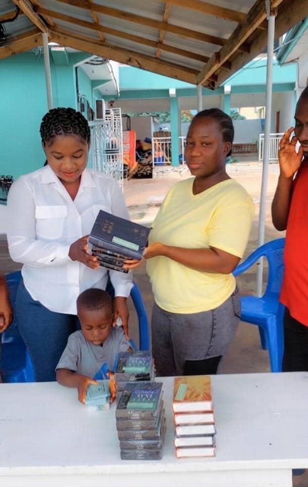 Lady Portia handing a Bible to a child during a church Bible donation