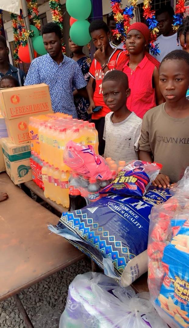 Children standing beside crates of drinks and boxes of donated supplies